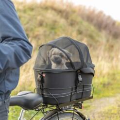 Hond onder de gesloten gaaskoepel van de fietsmand