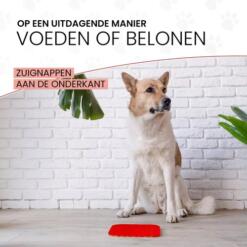 Hond wacht naast een rode likmat met zuignappen