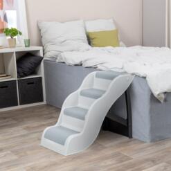 Lichtgrijze hondentrap tegen een bed in de slaapkamer