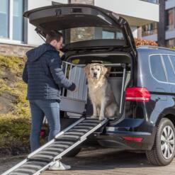 Trixie uitschuifbare loopplank telescoop 78 tot 175 cm 16 Hond zit in een bench in de auto met de loopplank tegen de laadrand
